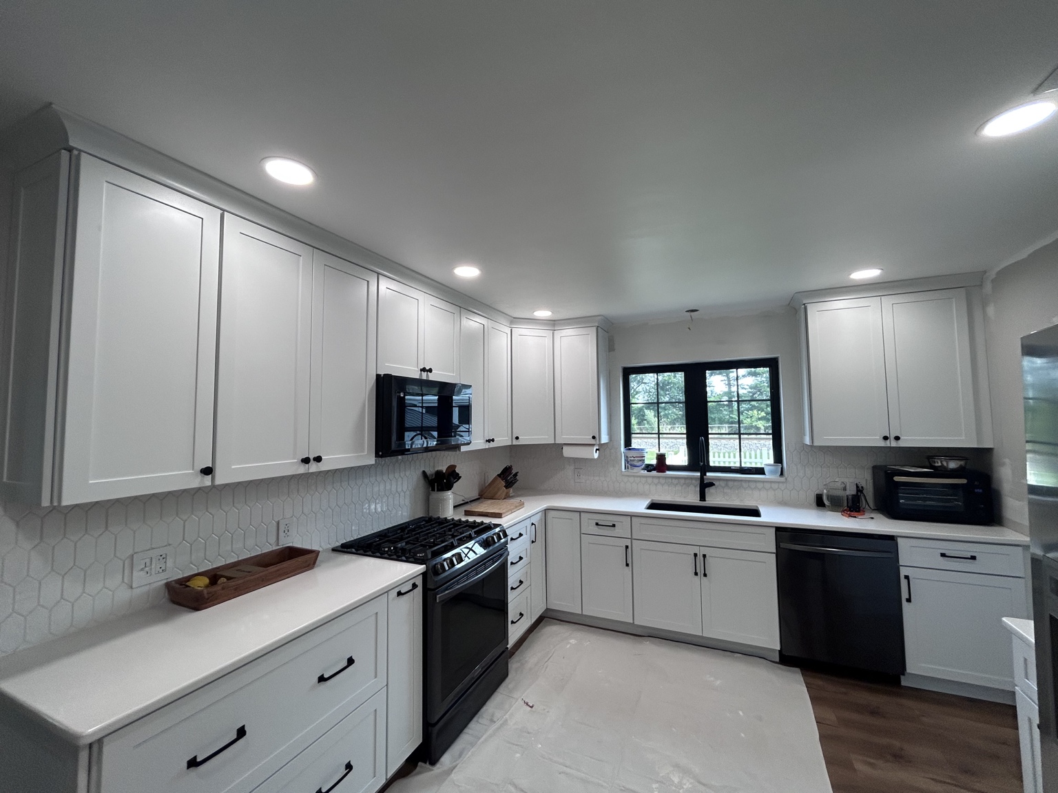 Kitchen with white shaker cabinets, geometric tile backsplash and black hardware